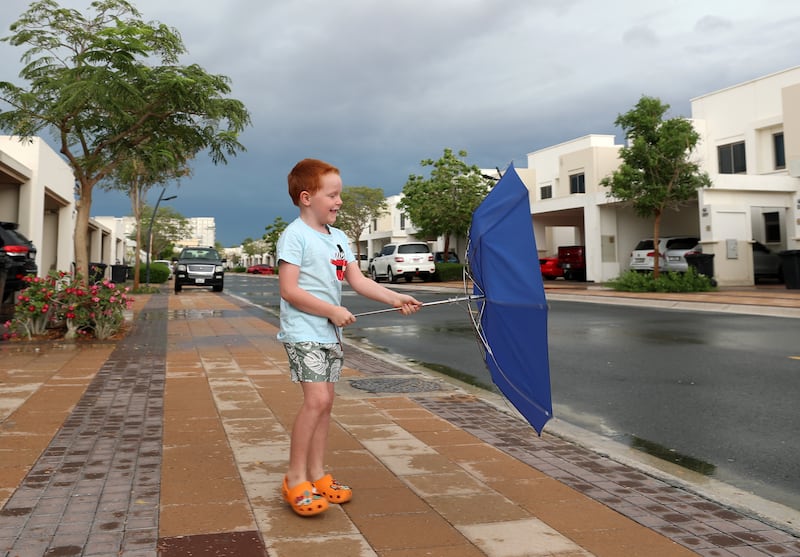 A young boy goes for a walk on a rainy day in Dubai. Chris Whiteoak / The National