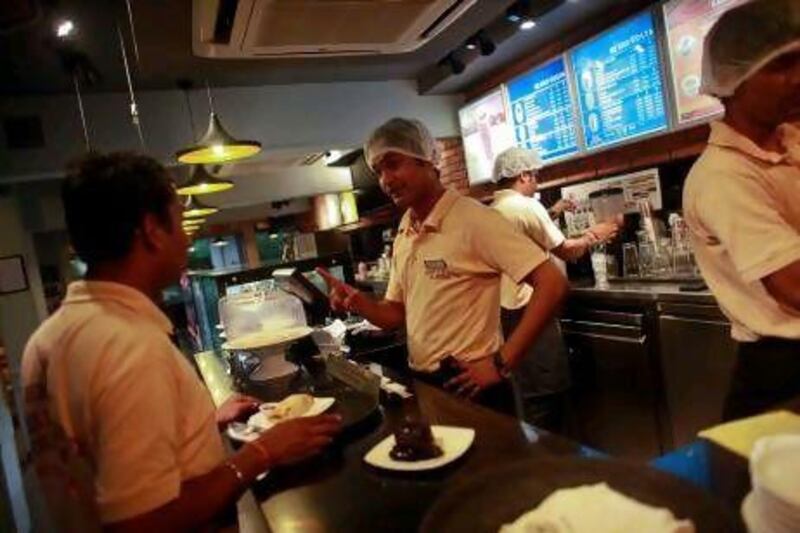 Employees prepare a meal for a customer inside a Costa Coffee shop in Mumbai. India's economic growth may have slowed to a near-decade low, but Britain's Costa Coffee and many other consumer-focused companies are expanding.