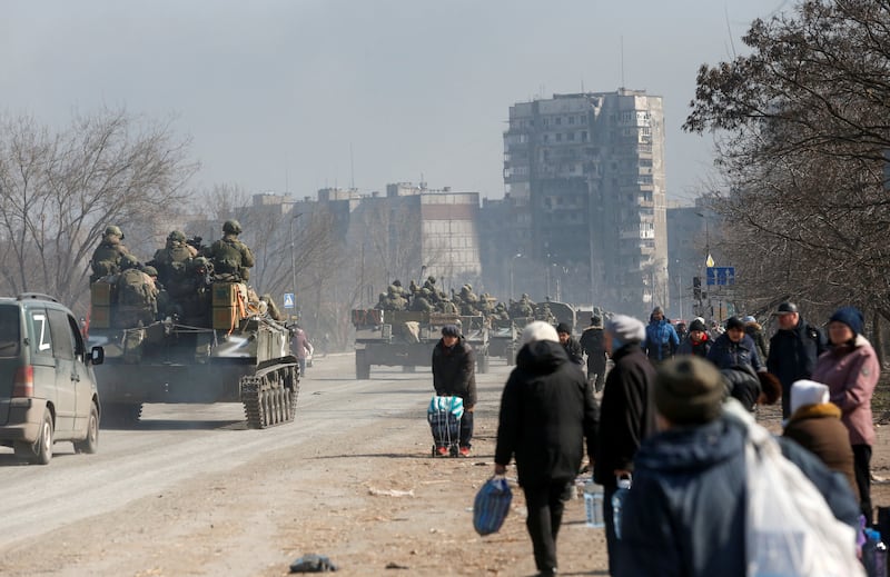 Pro-Russian troops drive armoured vehicles past local residents in the besieged Ukrainian port city of Mariupol. Reuters