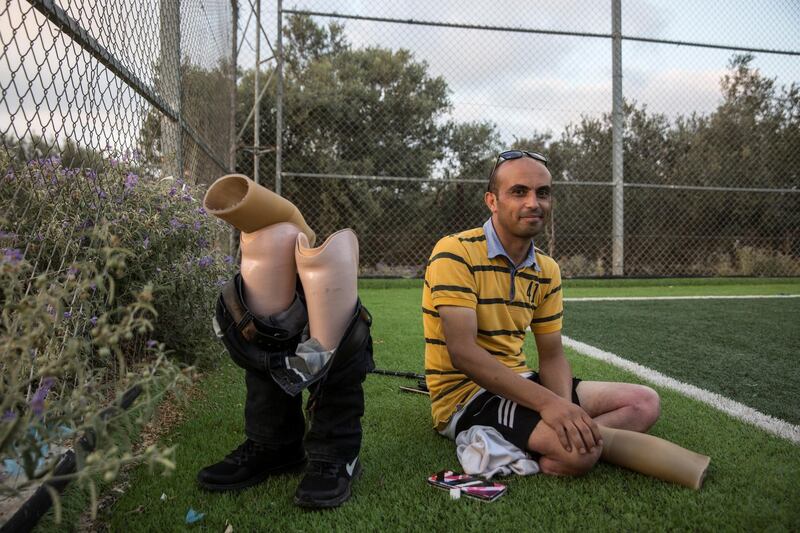 Mahmoud al-Naouq, the administrative manager of Gaza's first amputee football team, takes a break from his prosthetic legs as he watches from the side as the team practices at the Deir Al Balah municipal ball field on July 16,2018 . He lost both of his legs during the 2014 Israeli attack on Gaza on two different occasions .

"When my brother told me I lost both of my legs, I looked down and said God gave me these legs for 30 years and now I am going to be even better", said Mahmoud.
(Photo by Heidi Levine for The National ).
