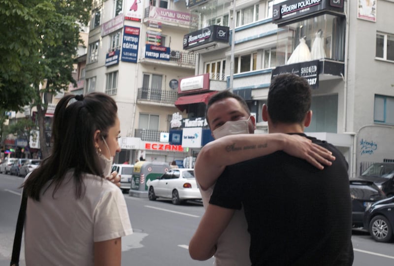 A man wearing a face mask to protect against the spread of coronavirus, embraces a friend in city the centre, in Ankara, Turkey. AP Photo