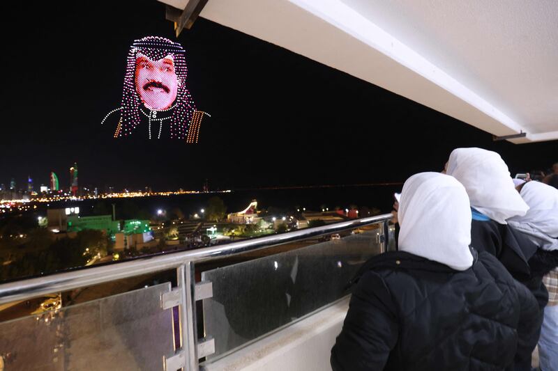 Onlookers admire an image of the Emir of Kuwait, Nawaf Al-Sabah