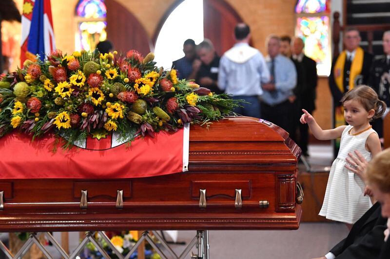 Charlotte O'Dwyer, the daughter of Rural Fire Service volunteer Andrew O'Dwyer, stands in front of her father's casket during the funeral at Our Lady of Victories Catholic Church in Horsley Park, Sydney. Reuters