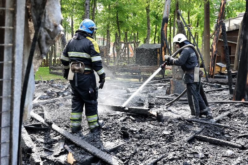 Firefighters damp down the ashes of a fire that destroyed a children's play area in Gorky Park in Kharkiv, Ukraine.  EPA