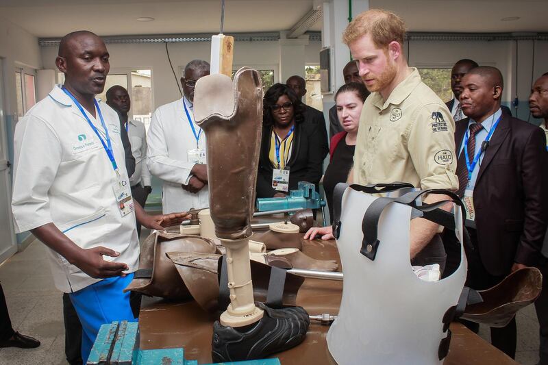 Prince Harry examines a prosthetic. EPA