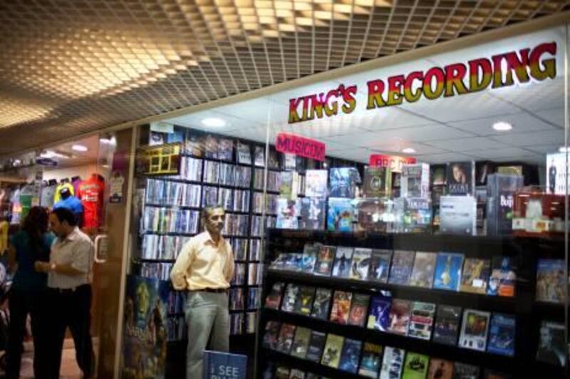 Salesman Muin Hasan, Indian, takes a break in restocking merchandise while he works at the Kings Recording, a movie and music store in the Hamdan center in downtown Abu Dhabi, on Tuesday, June 14, 2011. Kings Recording is the oldest business at the shopping center with a 30-year-old history there. (Silvia Razgova / The National)

Names, all CQ:
Iranian Hamzah Ansari, owner (grey)
Indian Abdul Rashid (brown shirt with stripes)
Indian Muin Hasan (orange shirt)
Texan Leah Byrd (blond lady with two daughers):
Mary, 17, (blonder hair) and Abigail, 16,
Ahmed Rashid, UEA,