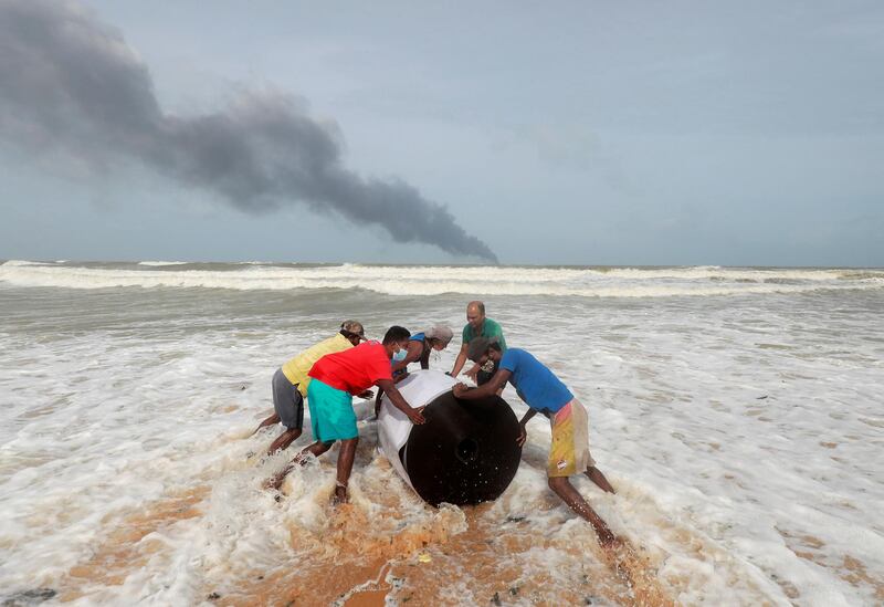 Villagers from Ja-Ela salvage cargo off the 'MV X-Press Pearl' container ship, on fire in the distance off Colombo harbour in Sri Lanka. Reuters
