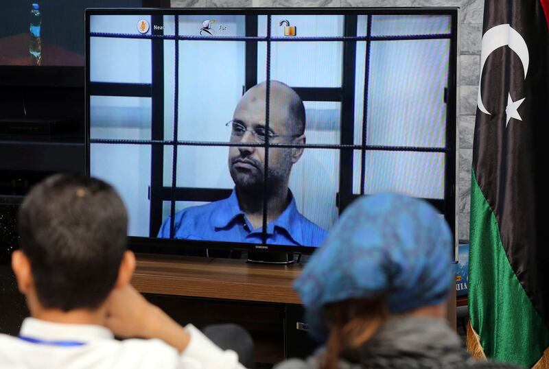 Journalists watch as unseen judges question Saif Al Islam (C) as he is broadcasted live from the western Libyan city of Zintan, from inside a room in Tripoli on April 27, 2014. Mahmud Turkia / AFP