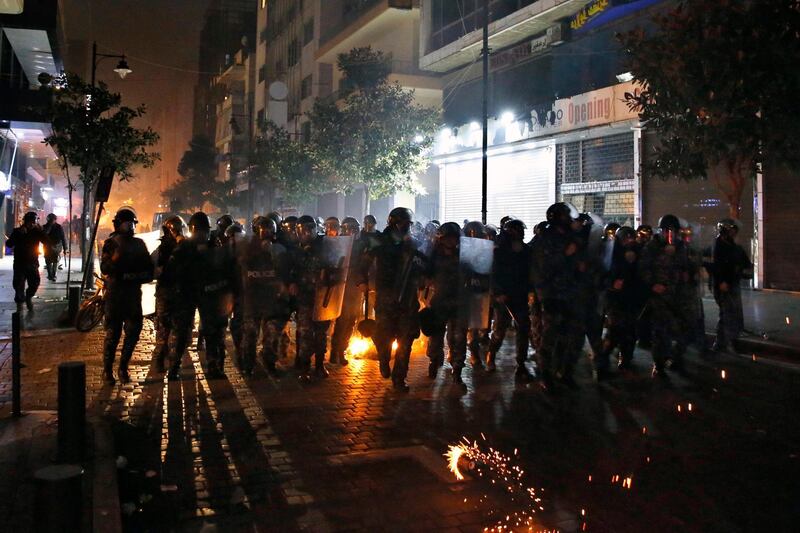 Riot police run toward anti-government protesters, during ongoing protests against the Lebanese central bank's governor and against the deepening financial crisis, at Hamra trade street, in Beirut, Lebanon.  AP