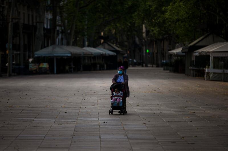 A woman pushes a buggy as they walk along the Ramblas in Barcelona, Spain, as the lockdown to combat the spread of coronavirus continues. Health authorities in Spain are urging parents to be responsible and abide by social distancing rules a day after some beach fronts and city promenades filled with families eager to enjoy the first stroll out in six weeks. AP