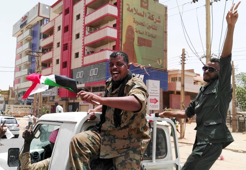 Members of the Sudanese security forces wave their national flag and flash the "V" for victory sign on April 11, 2019 in the capital Khartoum.  AFP
