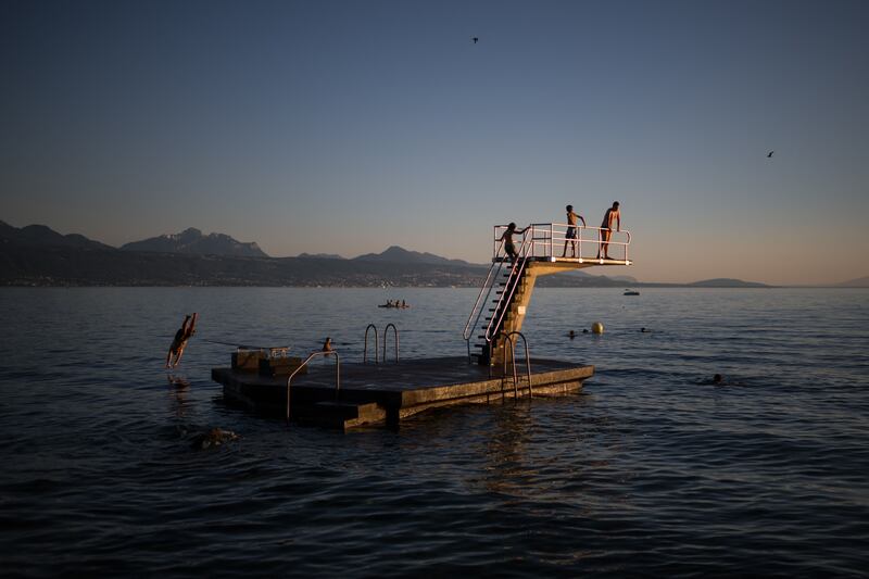 People dive from a platform on Lake Geneva, near Lausanne, Switzerland. AFP