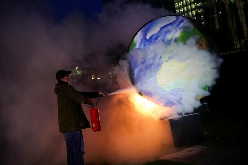 A person uses an extinguisher towards a burning paper-made globe during a demonstration against the fossil fuel industry, in front of the headquarters of the European Central Bank (ECB), in Frankfurt, Germany. REUTERS