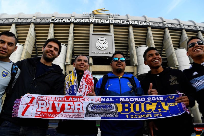 Supporters display a River Plate and Boca Juniors football teams scarf in front of the Santiago Bernabeu stadium in Madrid. AFP
