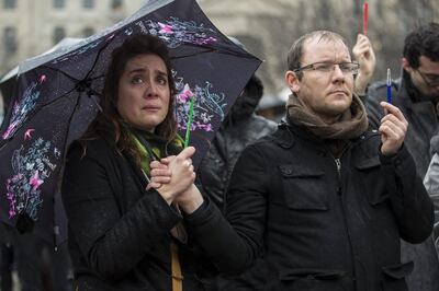 A woman, grasping a symbolic pencil, is moved to tears as people gather in front of Notre Dame cathedral for a minute of silence in memory of the 'Charlie Hebdo' victims in 2015. EPA