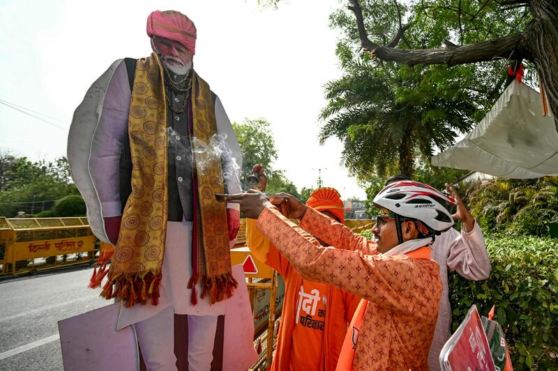 A supporter of Prime Minister Narendra Modi performs rituals next to a cut-out of the BJP leader outside the party's headquarters in New Delhi. AFP