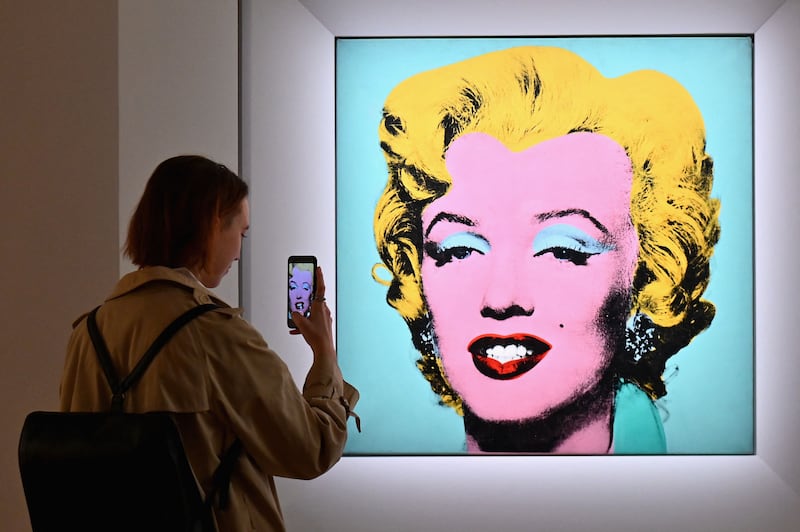 A woman takes a photo of Andy Warhol's 'Shot Sage Blue Marilyn' during Christie's 20th and 21st Century Art press preview at Christie's New York, New York. AFP