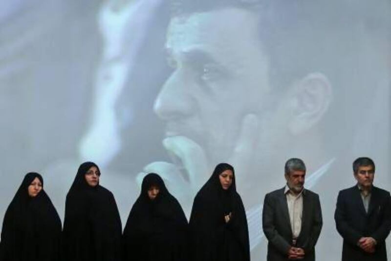 Family members of Iran's slain nuclear scientists and the chief of Iran's Atomic Energy Organization, Fereidoun Abbasi, right, in a ceremony marking Iran's National Day of Nuclear Technology, with president Mahmoud Ahmadinejad in the background.