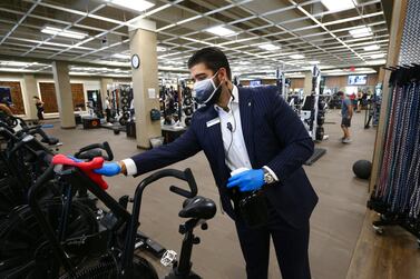 A sales manager at a health club disinfects exercise equipment as the full service facility remains open even as Arizona Governor Doug Ducey has issued an executive order for all gyms to close due to the surge in cases. AP Photo