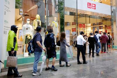 People wait in line at a Uniqlo clothing store at Ginza shopping area in Tokyo, Friday, June 19, 2020. Japanese shoppers queued up in a long line at Uniqlo stores and others clogged up the companyâ€™s online shopping site Friday as they rushed to buy washable face masks made from the fashion brandâ€™s fabric for popular underwear line for summertime use.(Kyodo News via AP)