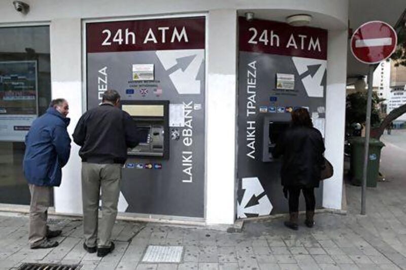 Cypriots withdraw money from ATMs outside a closed branch of Laiki Bank in Nicosia. Petros Giannakouris / AP Photo