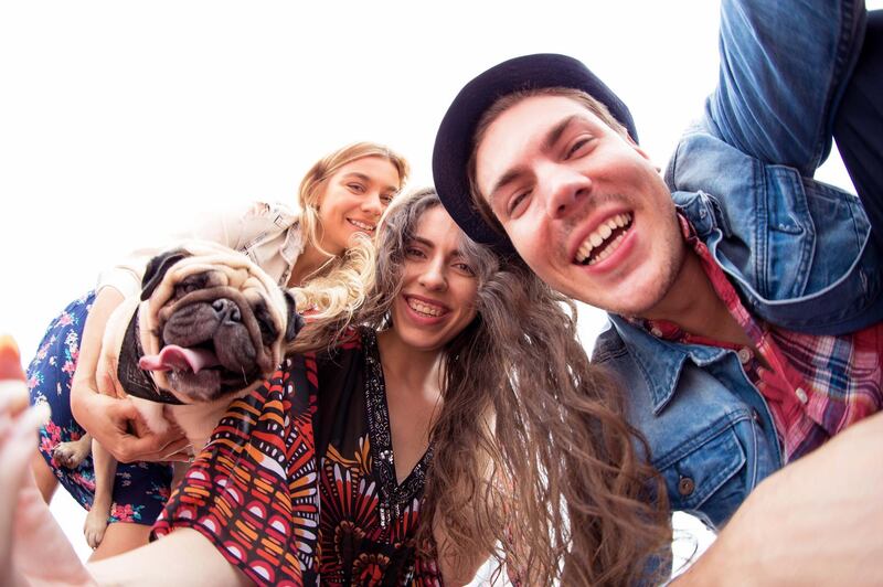 Selfie, Dubai, Travel, Friendship - Friends with their pug looking down to the camera for a photograph. Getty Images