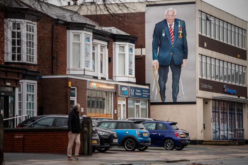 A man walks past a large painting of Captain Sir Tom Moore in Southport, UK. Getty Images