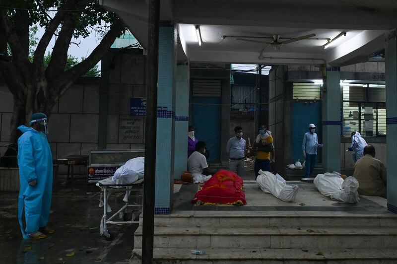 The bodies of people who died due to the Covid-19 coronavirus are seen line up on the ground upon been brought up to at a crematorium in New Delhi on May 6, 2021. / AFP / Prakash SINGH
