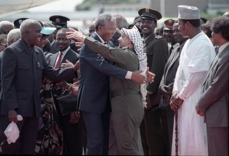 Nelson Mandela (L) is embraced by PLO leader Yasser Arafat as he arrives at Lusaka airport February 27, 1990.  REUTERS/Howard Burditt