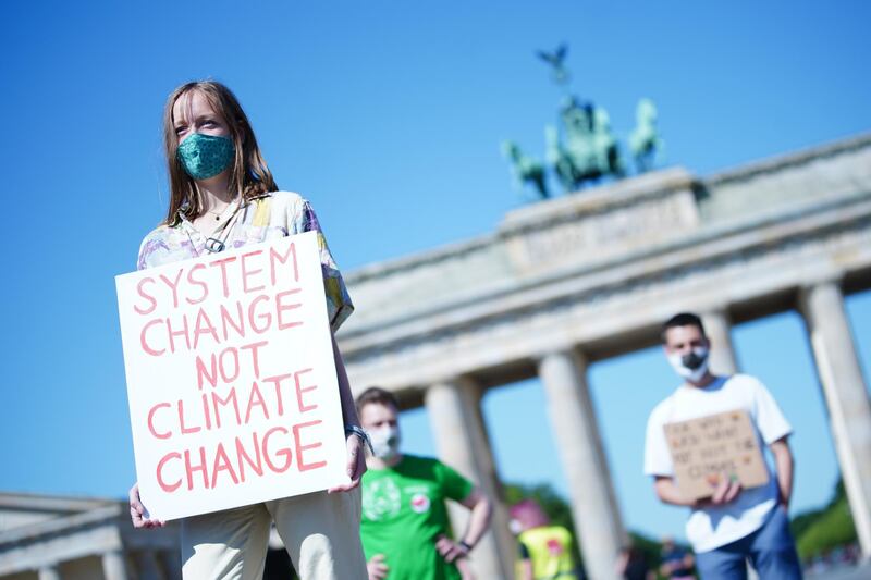 epa08459661 A protester holds a cardboard reading 'system change not climate change' during a Fridays for Future protest in Berlin, Germany, 02 June 2020. Fridays for Future, the Equal Welfare Association (Paritaerischer Gesamtverband) and German united services union Ver.di attended a joint press conference on joint demands with ecological and social fairness for economic stimulus measures on the occasion of the consultations of the German government on the economic stimulus package.  EPA/CLEMENS BILAN