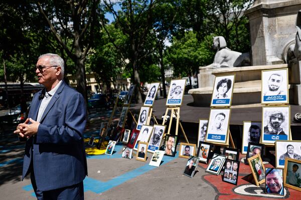 Brother of Mazen Dabbagh, Obeida Dabbagh stands next to pictures for Syrian victims in a Paris park. 