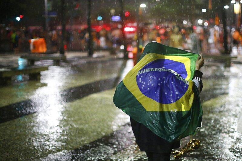 A Brazil fan walks in the rain in Rio de Janeiro after watching a broadcast of Brazil's 7-1 loss to Germany on Tuesday at the 2014 World Cup semi-finals in Belo Horizonte, Brazil. Jorge Silva / Reuters / July 8, 2014