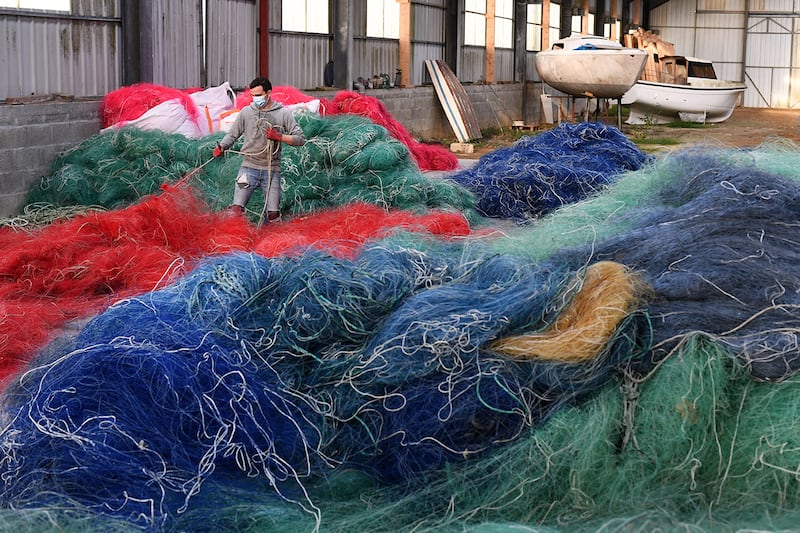 A worker sorts out used nylon fishnets at the warehouse of the Fil & Fab company, specialized in the recycling and sale of plastic from nylon fishing nets, in Plougonvelin, western France on November 12, 2020. - The company Fil&Fab, created in 2019 in the Bretagne region by three young designers, weaves its fabric with the aim of eventually launching objects that are 100% made from recycled fishing nets. (Photo by Fred TANNEAU / AFP)