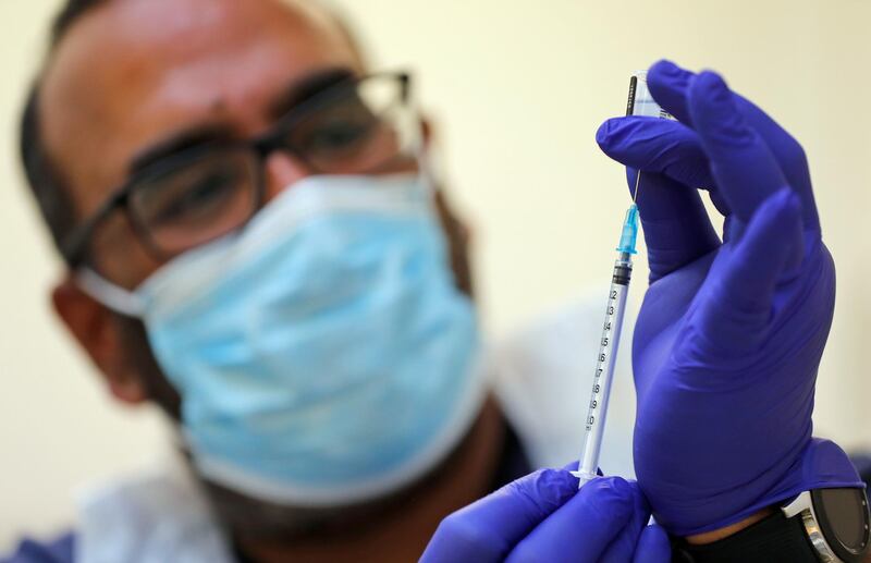 Doctor PJ Suresh draws from a vial of the Pfizer/BioNtech COVID-19 vaccine at the Fullwell Cross Medical Centre in Ilford, London, Friday, Jan. 29, 2021. Local leaders are racing to reach out to ethnic minority communities, where people are often less likely to come forward to be inoculated. (AP Photo/Frank Augstein)