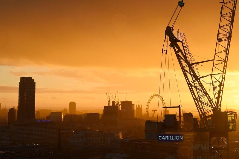 TOPSHOT - The sun sets behind a construction crane showing the branding of British construction company Carillion photographed on a building site in central London on January 15, 2018, with the skyline of the British capital in the background including the London Eye and the Houses of Parliament.  
The British government is keeping a "very close eye" on construction and outsourcing group Carillion, a senior minister said January 14, 2018, amid reports it could go into administration within days. / AFP PHOTO / Daniel SORABJI
