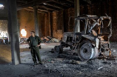 A Ukrainian farm worker stands by a tractor destroyed in Russia's invasion. Getty 