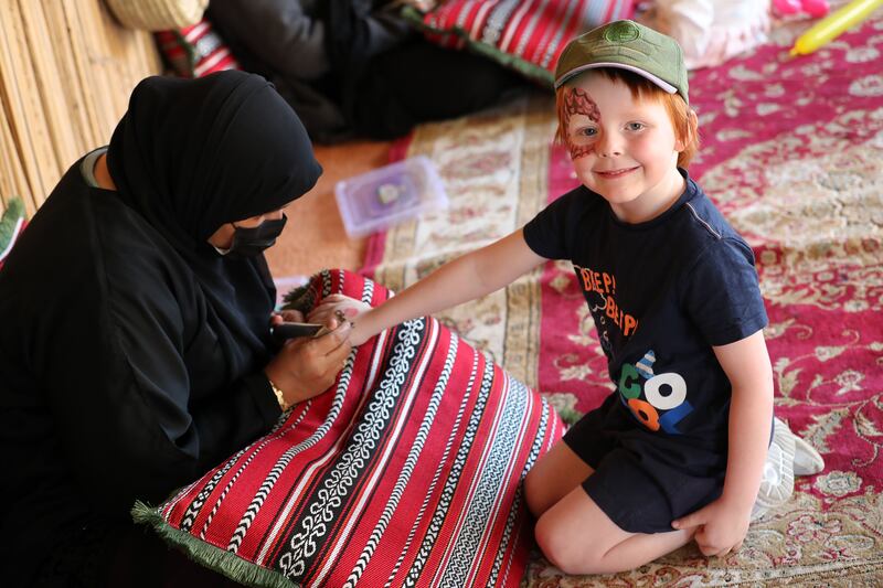 Sobia paints henna on Charlie, aged 5, at the Saturday Market at Al Ain Oasis