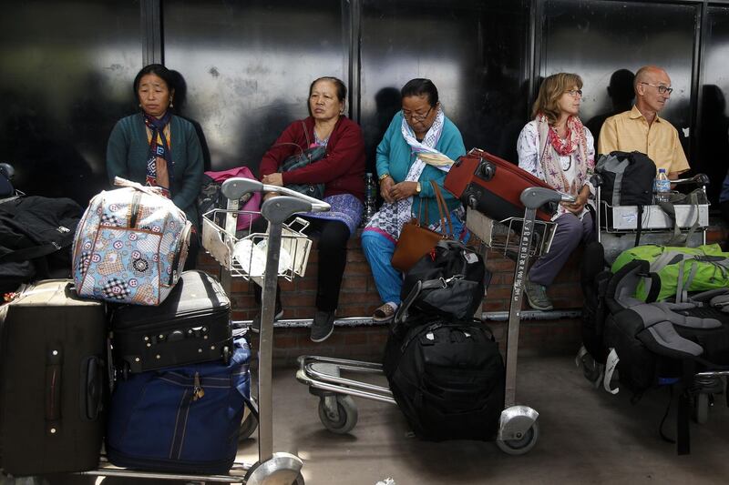 Stranded travellers sit outside the international airport in Kathmandu on April 20, 2018, after a plane skidding off the runway disrupted flights for 12 hours until just before midday on April 20, 2018. Sunita Dongol / AFP