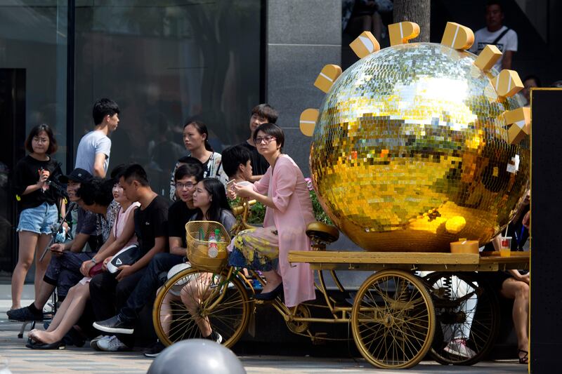 A woman sits on a tricycle painted gold and used as a marketing gimmick in Beijing, China, Tuesday, Aug. 8, 2017. China's trade growth weakened in July in a negative sign for growth in the world's second-largest economy and global demand. (AP Photo/Ng Han Guan)