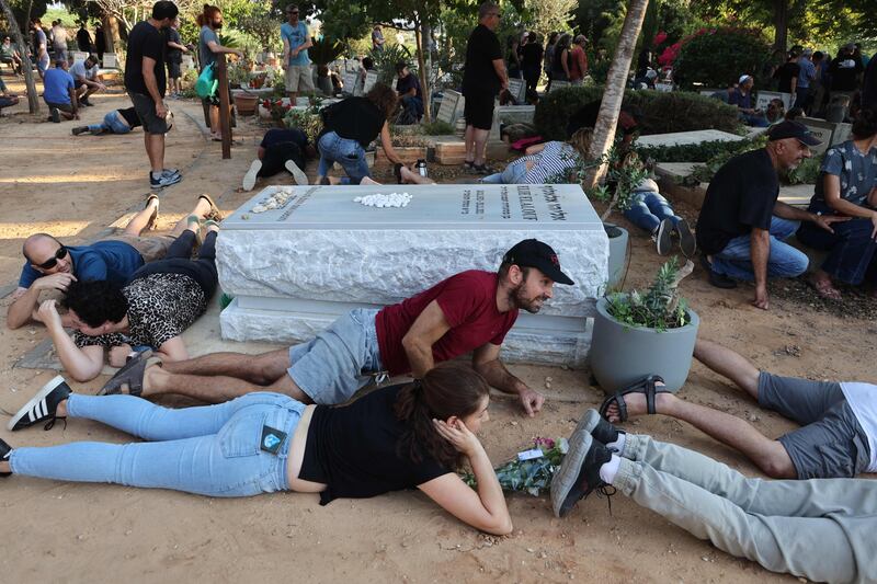 Mourners take cover as sirens sound during the funeral of Tom Godo, killed during the attack by Hamas militants on the Kibbutz Kisuffim last week, in Kibbutz Naan near Tel Aviv. AFP