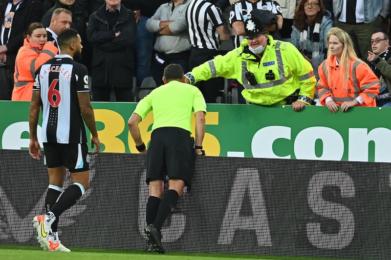 Referee Andre Marriner speaks to a policeman after a fan collapsed resulting in the match being halted. AFP