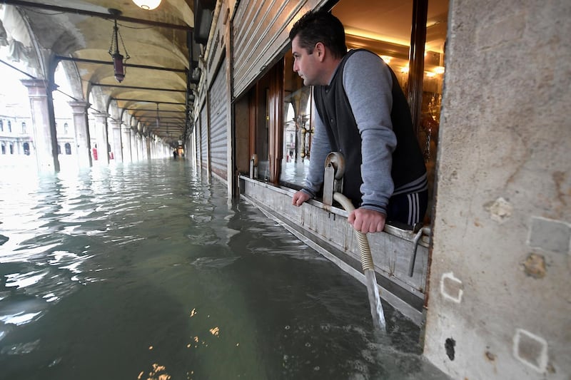 A man pumps water from a shop at the flooded St. Mark's Square, as high tide reaches peak, in Venice, Italy. REUTERS