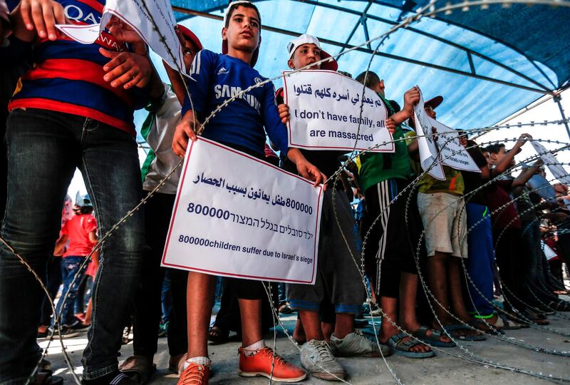 Palestinian children demonstrate with signs at the Erez crossing with Israel near Beit Hanun in the northern Gaza Strip on July 24, 2018 against Israel's blockade on the enclave.  / AFP / MAHMUD HAMS
