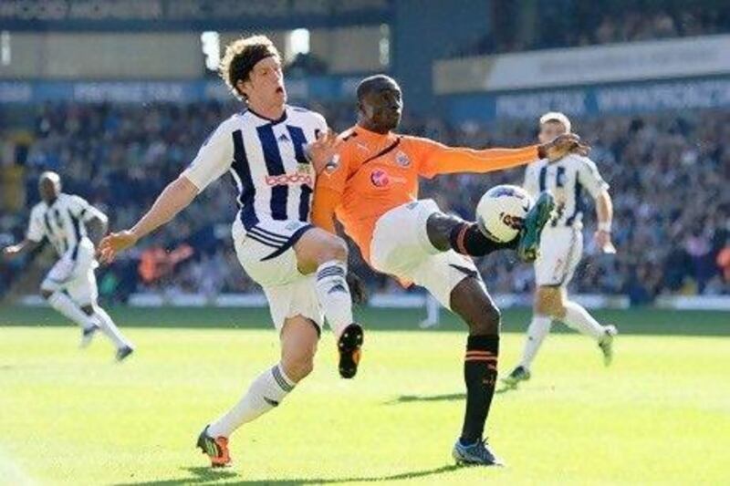 Papiss Cisse of Newcastle clears the ball as Billy Jones of West Brom closes in.