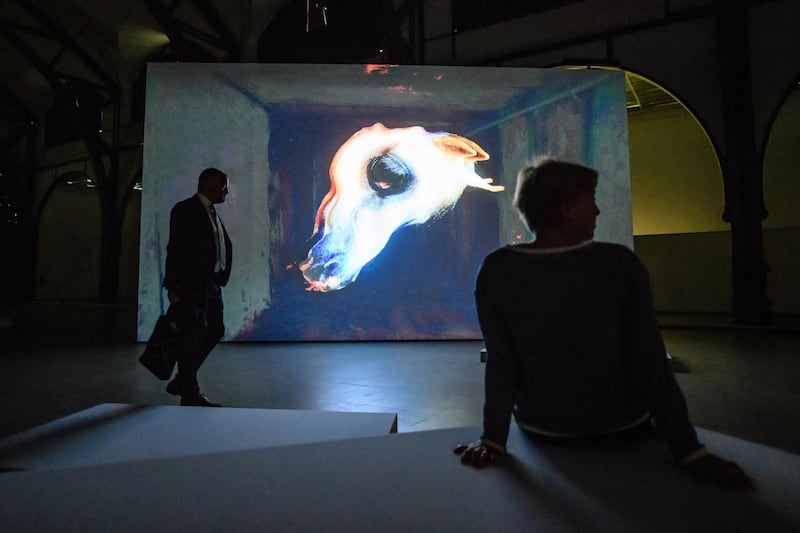 Visitors stand in front of a video installation of the artwork 'The Demon's Brain' by Polish artist Agnieszka Polska (not in the picture) at the 'Hamburger Bahnhof' exhibition hall in Berlin.  EPA
