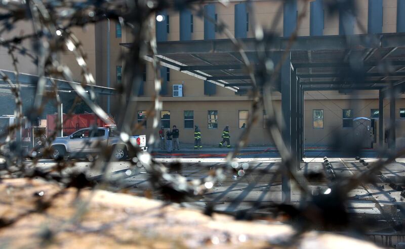 US embassy staff and guards are seen through the barbed wire fence as members of the Popular Mobilisation Forces and their supporters attack the entrance of the US embassy in Baghdad.  EPA