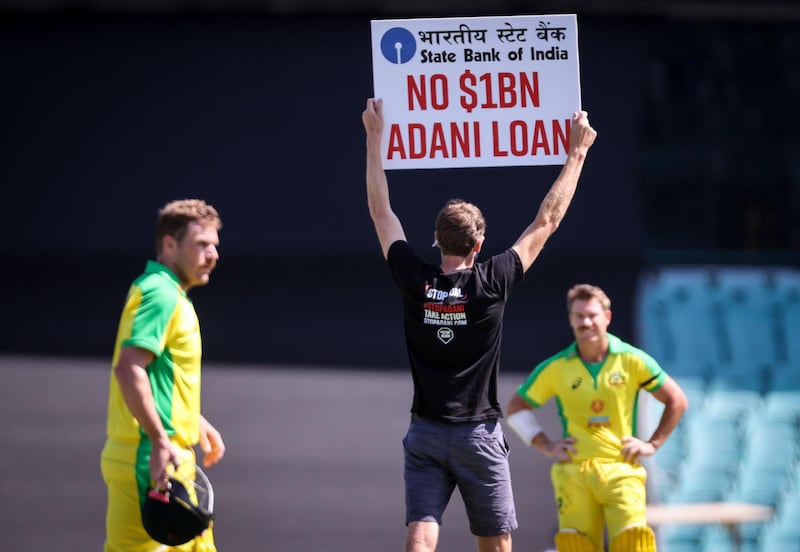 Australia's captain Aaron Finch and teammate David Warner watch as a protester holds a sign at the Sydney Cricket Ground. AFP