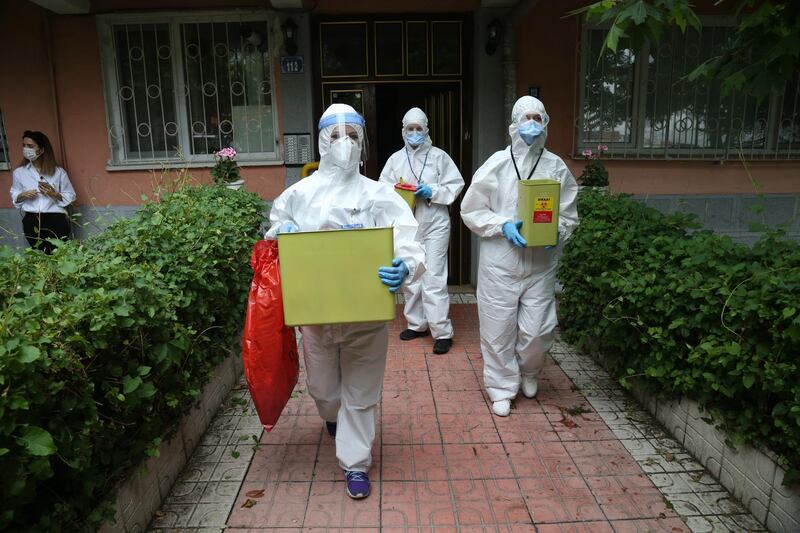 Medical workers in protective gear leave an apartment with samples during a testing programme at a home in Ankara, Turkey.  EPA