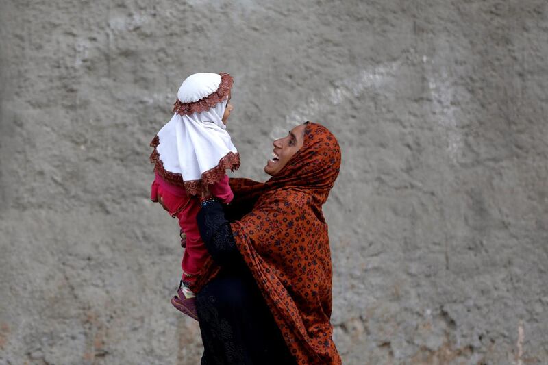 A mother plays with her baby, as they are heading to a nearby bus stop early cold morning in Karachi, Pakistan. Reuters