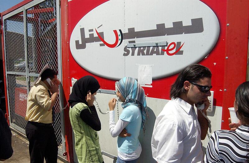 FILE - In this July 25, 2006, file photo, Lebanese refugees at the Syrian-Lebanese border crossing at Jdaidet Yabous talk with their relatives in Lebanon through mobile phones provided free by Syrian telecommunication company Syriatel. The unprecedented public crackdown on Syria's wealthiest businessman Rami Makhlouf, a close cousin of Bashar Assad, comes as the embattled president seeks to consolidate power and rein in war profiteers. Syria is preparing for a new phase of economic hardship and U.S.-led sanctions that some say might be more difficult to weather than war. (AP Photo/ Bassem Tellawi, File)